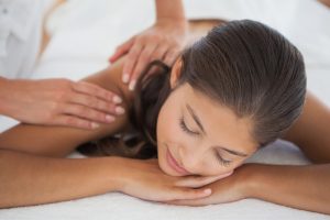 Relaxed woman enjoying a neck and shoulder massage by a masseuse at a pamper party. Total indulgence.